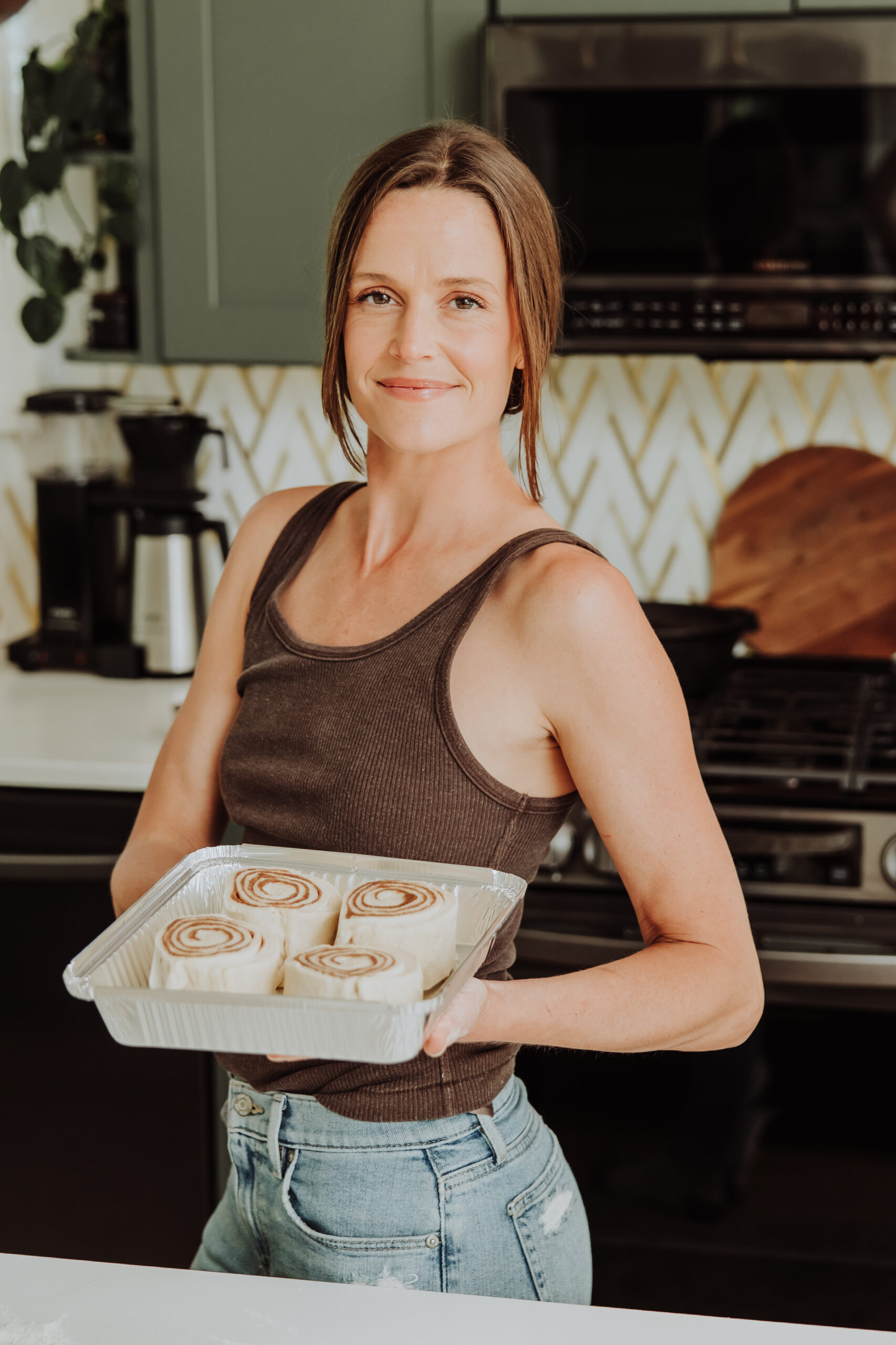 Kelli holding a pan of cinnamon rolls